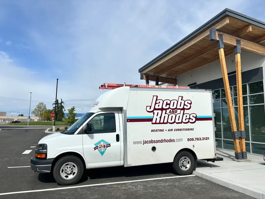 A white Jacobs and Rhodes service van with the 60-years badge and the 509.783.3121 number on its side