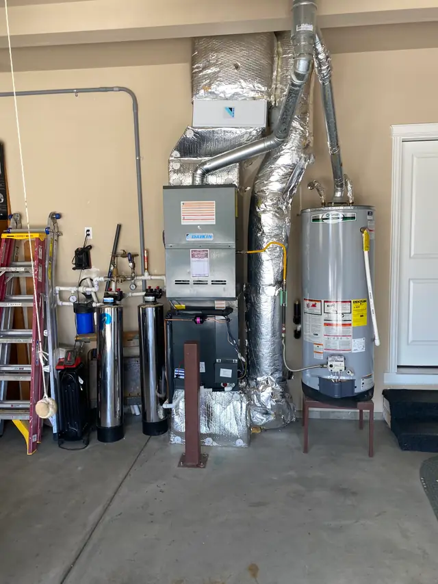 A finished Daikin furnace and ductwork install in a garage, with the Jacobs and Rhodes service sticker on the unit